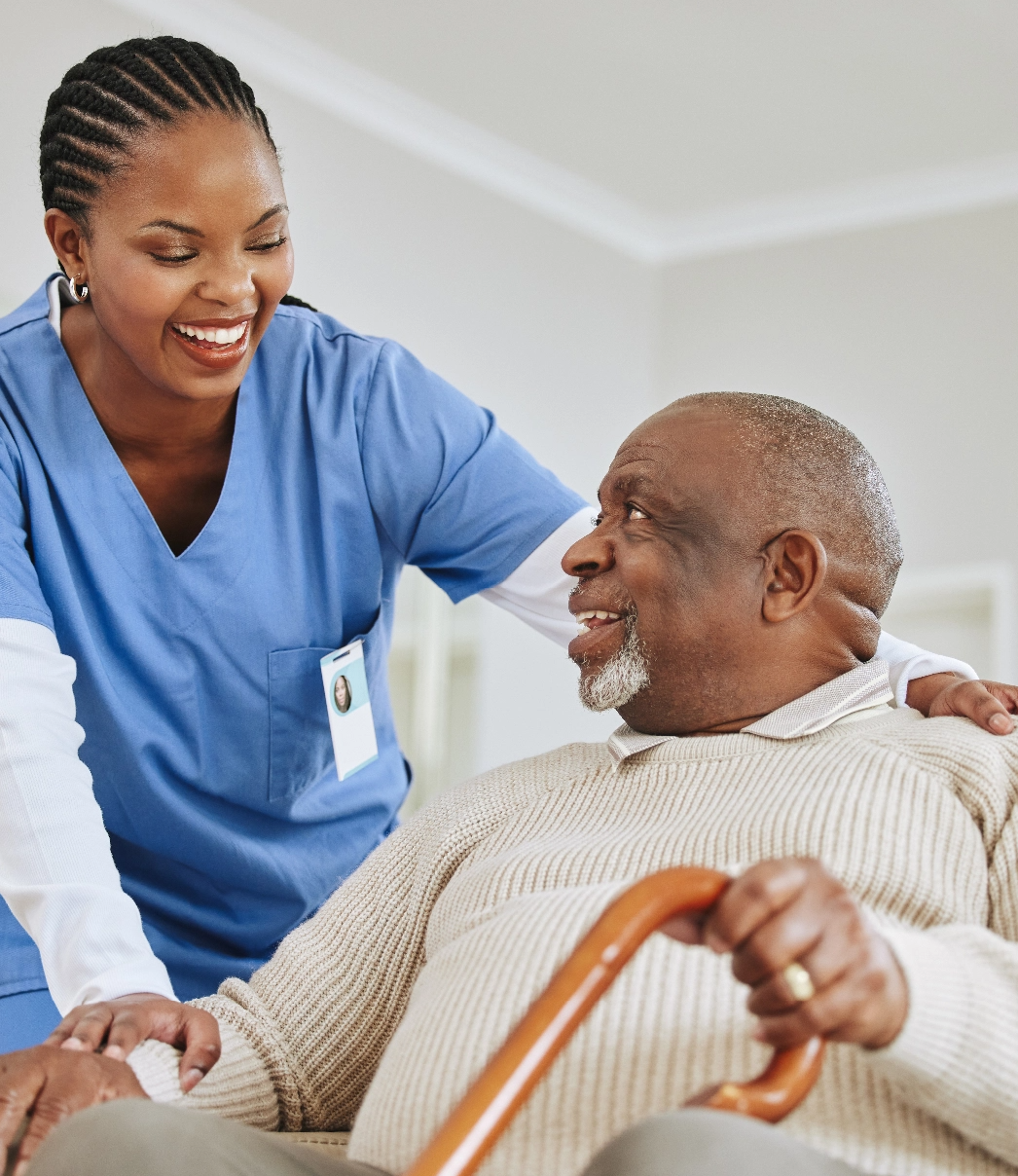 A nurse caring for a seated patient, they're both smiling